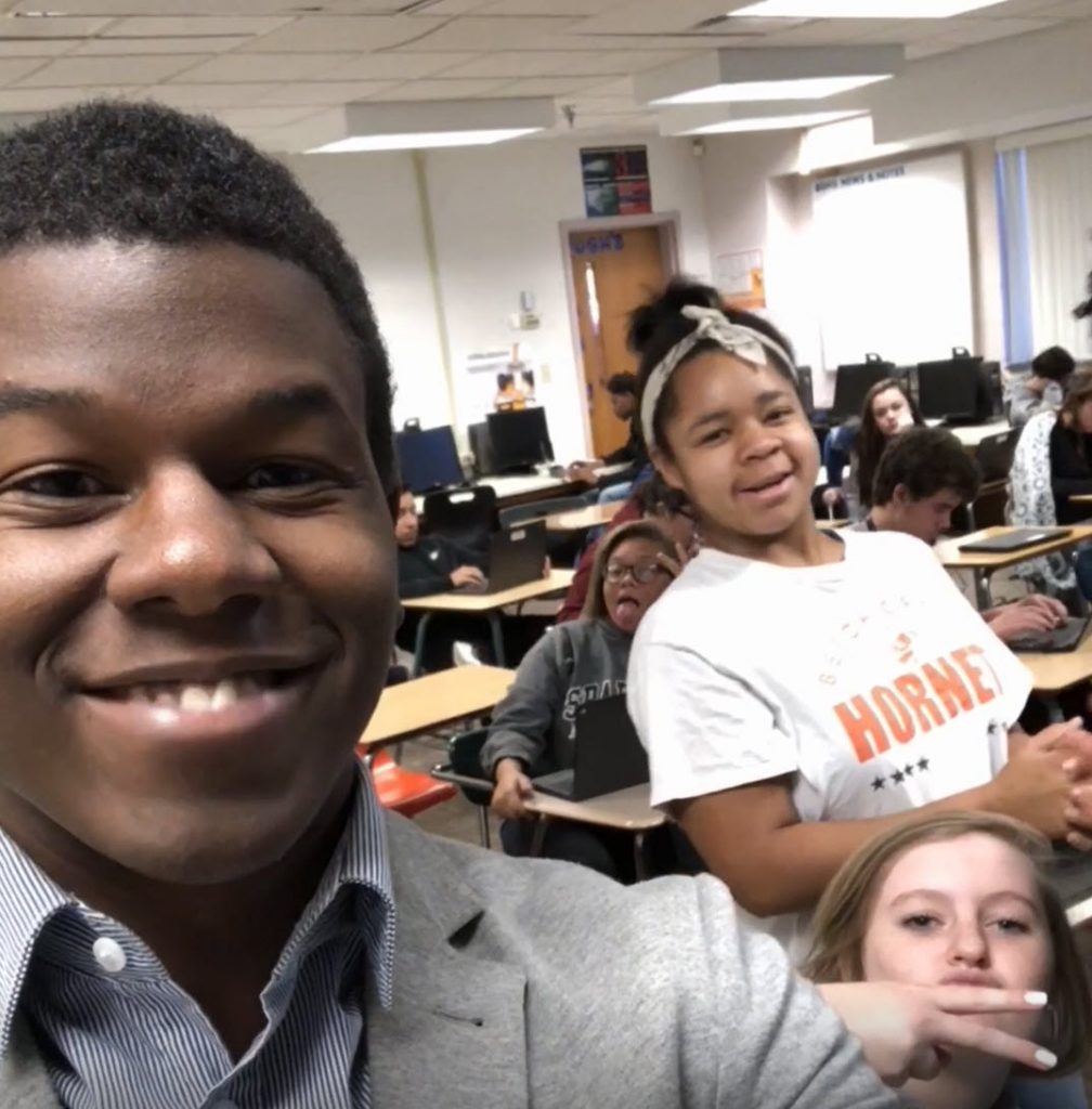 Rashad taking a selfie with students in the background