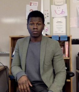 Rashad sitting in a desk chair and looking at the camera